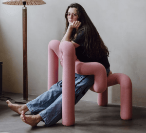 designer woman with glasses and ripped jeans sitting reverse cowgirl on pink ekstrem